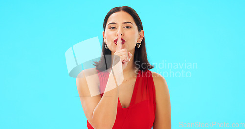 Image of Finger, lips and face of happy woman on blue background, studio and privacy news. Portrait of female model, smile and silence of noise, shush and hands on mouth in secret, quiet announcement or emoji