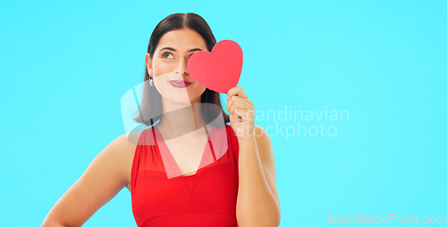 Image of Paper heart, happy woman and face on blue background, studio and backdrop. Portrait of female model in red dress with shape of love, trust and romance for valentines day, flirting and elegant smile