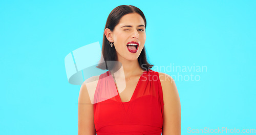 Image of Happy, woman and winking face on blue background, studio and color backdrop. Portrait, female model and smile for wink, secret and fun mood in red dress, personality and happiness for flirting emoji