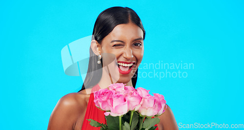 Image of Flower bouquet, smile and beauty woman wink with nature gift, sustainable agriculture portrait or natural present. Funny flirty joke, floral studio roses and female person laugh on blue background