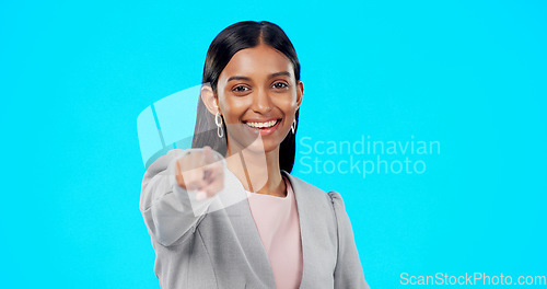 Image of Portrait, pointing and you with a woman on a blue background in studio for option, selection or choice. Smile, happy and we are hiring with a young female employee in business making a decision