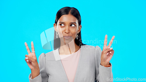 Image of Face, smile and Indian woman with peace sign, support and happiness against blue studio background. Portrait, female and lady with smile, hand gesture and success with solidarity, winner and victory