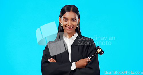 Image of Lawyer, face and happy woman with gavel in studio, blue background and color backdrop. Portrait, female judge and legal attorney with arms crossed, smile and confidence for justice of constitution