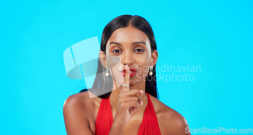 Image of Secret, face and woman with finger on lips in studio, blue background and privacy sign. Portrait of indian model, silence and shush for quiet, gossip and whisper of confidential mystery, emoji or