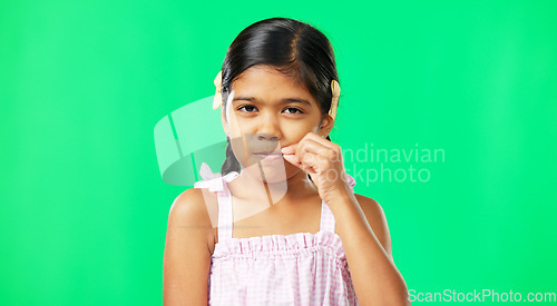 Image of Children, secret and trust with a girl on a green screen background in studio zipping her lips. Portrait, kids and silent with an adorable little female child making a promise to keep quiet