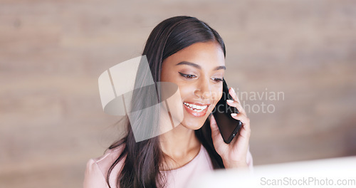 Image of Secretary talking on a phone while working on a computer at a front desk. Cheerful young receptionist with a friendly tone scheduling appointments and confirming meetings with clients in an office