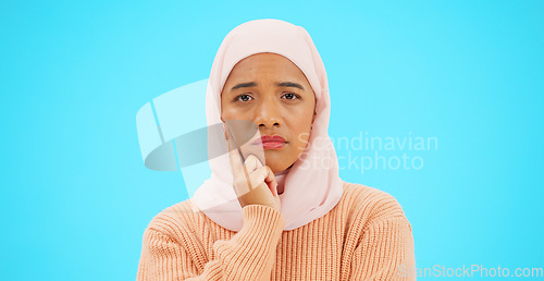Image of Muslim woman, thinking and idea with hand on face for mockup, advertising or thought. Serious islamic female with hijab and emoji for doubt, sad and to think about option on a studio blue background