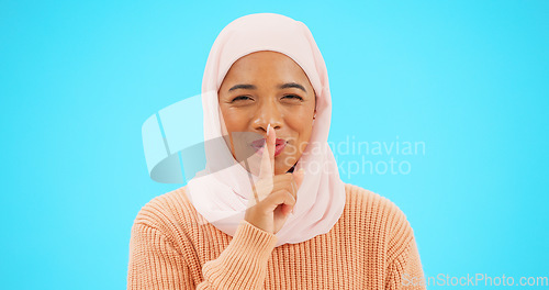 Image of Muslim woman, finger on lips and secret with hand on mouth for mockup, advertising or promotion. Islamic female with hijab, face emoji or laugh for sale, gossip or surprise on studio blue background