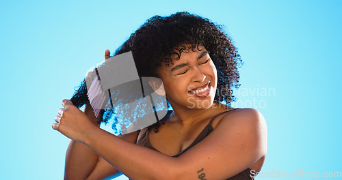 Image of Frustrated, knot and black woman with comb for hair on blue background with problem, hairstyle frizz and damage. Beauty salon, hairdresser and sad girl brush afro for wellness, grooming and cosmetics