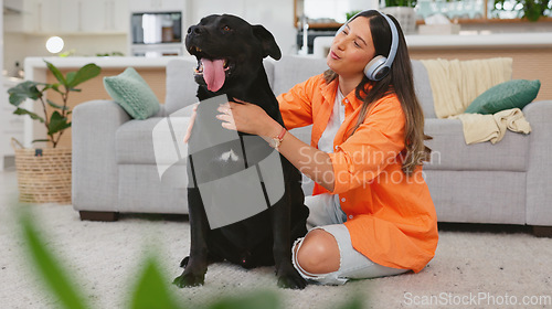 Image of Black dog scratch, woman and living room with animal and pet owner care in a home. Headphones, gen z person and labrador in a house with happiness and a smile listening to music with puppy love