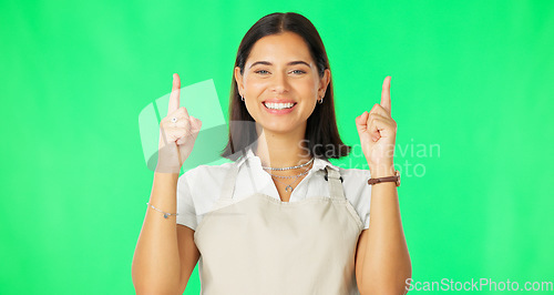 Image of Woman, smile and portrait on green screen while pointing finger up at mockup space with apron. Female model happy about advertising business or promotion or choice in air on a studio background