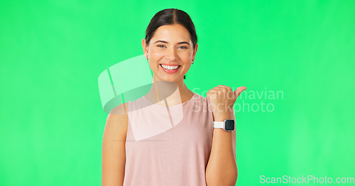 Image of Woman face, pointing gesture and green screen with happiness and smile showing advertisement. Portrait, isolated and studio background with a happy young female point to show mock up announcement