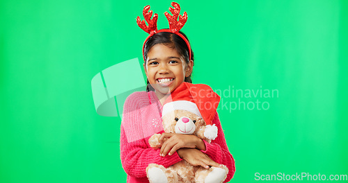 Image of Happy, Christmas and face of a child with a teddy on a green screen isolated on a studio background. Bear, smile and portrait of a girl kid hugging a toy while excited for the festive season