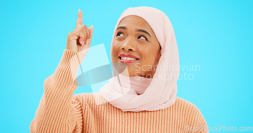 Image of Happy muslim, woman and pointing finger portrait with space for mockup, advertising or promotion. Islamic female with hand, smile and hijab for announcement, Allah or God and sale on blue background