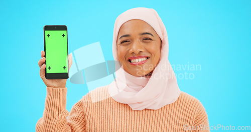 Image of Muslim, phone or green screen and a woman on a blue background in studio holding a display with tracking markers. Islam, mobile contact and an attractive young female showing a screen for marketing