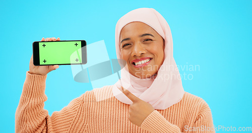 Image of Islam, phone or green screen and a woman on a blue background in studio holding a display with tracking markers. Muslim, mobile contact and an attractive young female showing a screen for marketing