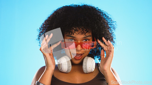 Image of Trendy, gen z and face of a black woman in a studio with accessories, sunglasses and fashion. Happy, afro and portrait of African female model with a cool, stylish and edgy style by a blue background