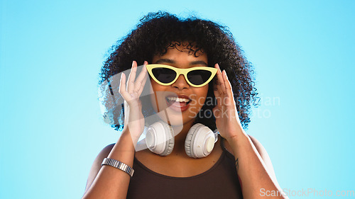 Image of Trendy black woman face isolated on blue background for beauty, cosmetics and fashion of gen z lifestyle. Confident african american person or model with cool sunglasses and headphones for summer