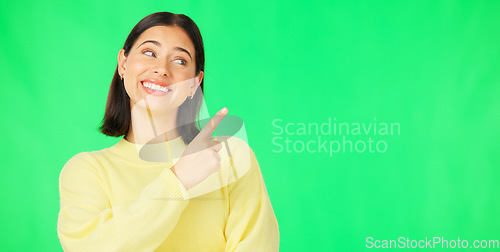 Image of Portrait, pointing and product placement with a woman on green screen in studio for marketing or advertising. Hand gesture, product placement and options with an attractive young female on chromakey