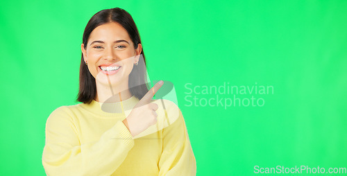 Image of Portrait, pointing and product placement with a woman on green screen in studio for marketing or advertising. Hand gesture, product placement and options with an attractive young female on chromakey