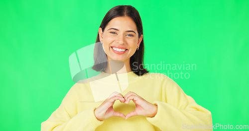 Image of Heart, hands and face of happy woman on green screen, studio or smile on color backdrop. Female model, portrait and finger shape of love, thank you or support of peace, emoji sign or care of kindness