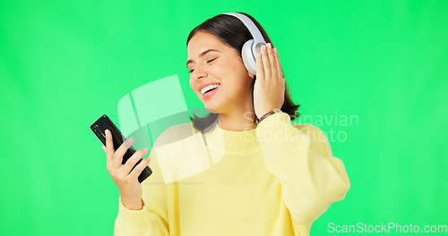 Image of Happy woman, phone and dancing with headphones on green screen for audio track against a studio background. Female with headset listening to music on smartphone enjoying dance to sound on mockup