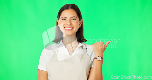 Image of Woman, happy and portrait on green screen while pointing finger at mockup space with apron. Professional female with a smile for advertising business choice or promotion on a studio background