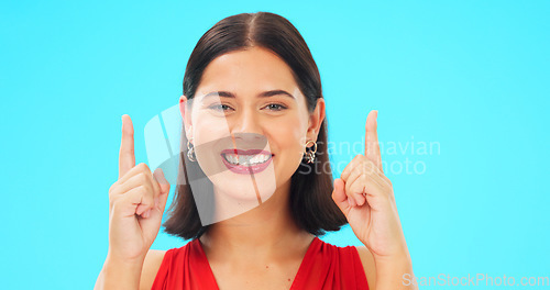 Image of Smile, face and woman on blue background pointing up to news on mockup color studio. Portrait of female model advertising promotion, product placement and presentation of commercial offer coming soon