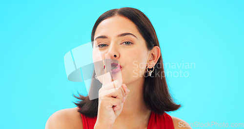 Image of Happy woman, blue background and secret wink of face, finger on lips and privacy. Portrait of female model, silence and quiet smile for gossip, whisper emoji or trust in surprise mystery announcement