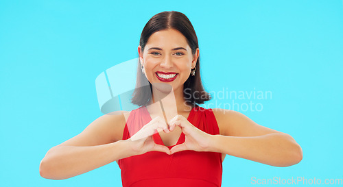 Image of Face, heart and hands of happy woman on blue background, studio and color backdrop. Portrait, female model and finger shape of love, support and kindness for care, thanks and emoji icon, sign or hope