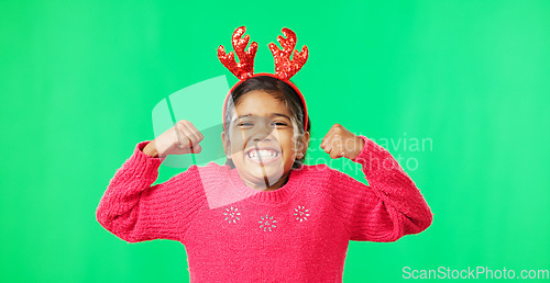 Image of Child portrait, christmas and antlers on green screen flexing strong muscles or arms for motivation. Smile on face of a girl kid on a studio background with reindeer headband for holiday celebration