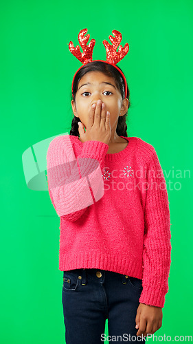 Image of Child, christmas and shocked on green screen for secret or sale studio background. Face of girl kid with antlers headband and hand on mouth for holiday celebration announcement, surprise or portrait