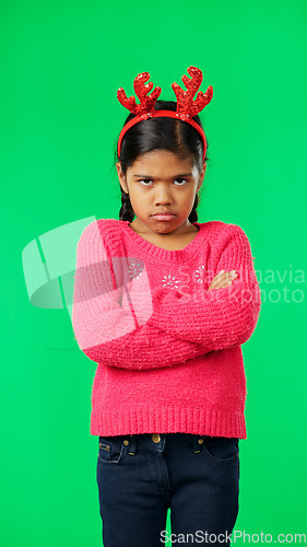 Image of Portrait, christmas and an unhappy girl on a green screen background standing arms crossed in anger. Kids, sad and frustrated with a miserable little female child looking moody, annoyed or upset