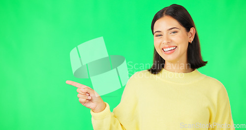 Image of Portrait, point and space with a woman on a green screen background in studio for marketing or product placement. Hand gesture, advertising and options with an attractive young female on chromakey