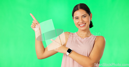 Image of Woman face, hands pointing and green screen with happiness and smile showing advertisement. Portrait, isolated and studio background with a happy young female point to show mock up announcement