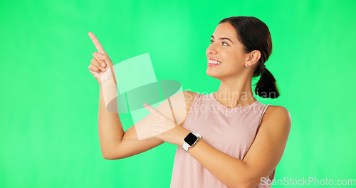 Image of Woman face, hands pointing and green screen with happiness and smile showing advertisement. Portrait, isolated and studio background with a happy young female point to show mock up announcement