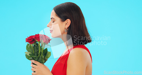 Image of Rose, smell and face of woman in studio with floral bouquet in celebration of love, romance or valentines day. Portrait, scent and girl happy, smile and excited for flowers against blue background