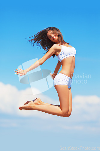 Image of Energy, happy woman and jumping in the air on a blue sky for freedom, summer body and happiness. Smile, excited jump and a girl in underwear for comfort, free and positivity with a boost in vitality