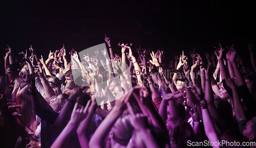 Image of Big crowd, hands and people at music festival or concert, neon lights and energy at live event. Dance, fun and excited fans dancing in arena at rock band performance or audience at weekend rave party