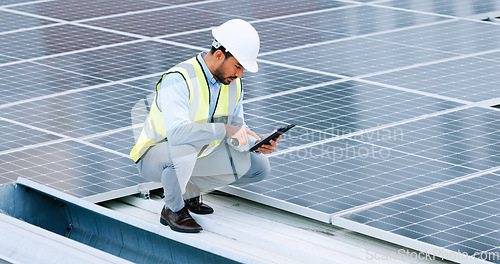 Image of Young engineer or contractor inspecting solar panels on a roof in the city. One confident young manager or maintenance worker smiling while installing power generation equipment and holding a tablet
