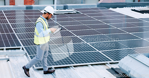 Image of Electrician checking solar panels technology on the roof of the building his working on. Professional engineer technician wearing a safety helmet looks closely at his modern renewable energy design