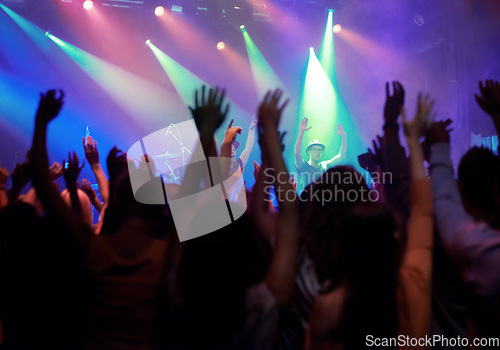 Image of Fans, people or dancing at concert, music festival or night party, neon lights or event energy. Dance, fun and show, excited crowd in arena and rock band musician in spotlight on stage performance.