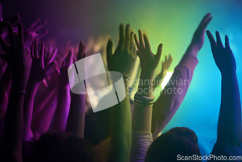 Image of Hands, neon and lighting for people at concert dancing, music festival or crowd with energy at night event. Dance, fun or group of excited fans in arena, rock band performance and disco color party