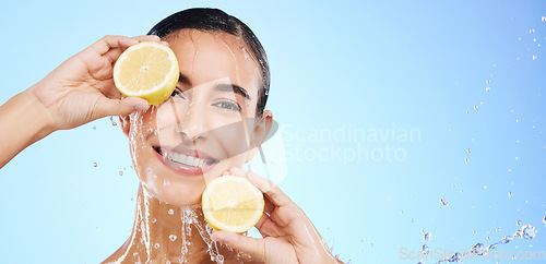 Image of Beauty, lemon and water splash with portrait of woman in studio for natural cosmetics, nutrition and mockup. Glow, fruits and hydration with female on blue background for vitamin c, face and skincare