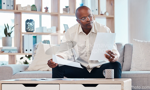 Image of Man reading paperwork in living room home for planning, budget report and investment contract. Black male, notes and remote work in lounge of tax documents, financial savings or insurance information