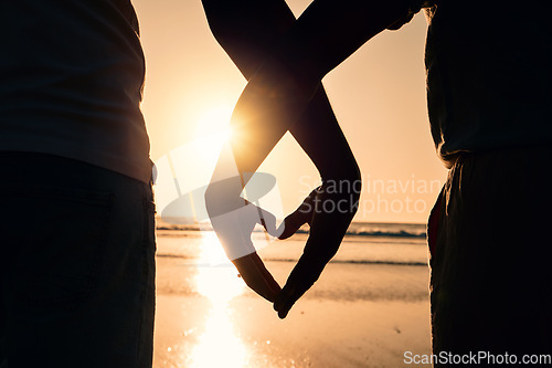 Image of Sunset, heart hands and couple on the beach while on a vacation, adventure or weekend trip. Romance, silhouette and closeup of man and woman with love gesture in the evening while on romantic holiday