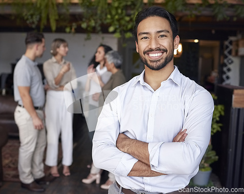 Image of Portrait, smile and a professional business man in the office, standing arms crossed with his team in the background. Corporate, happy and confident with a young male employee at a work function