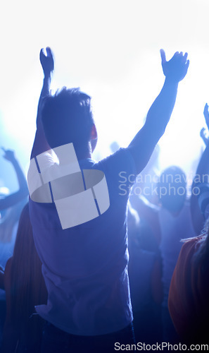 Image of Music festival, concert and man in crowd from back, dancing in neon lights and energy at live event. Dance, fun and excited fans in arena at rock band performance or audience at techno rave party.