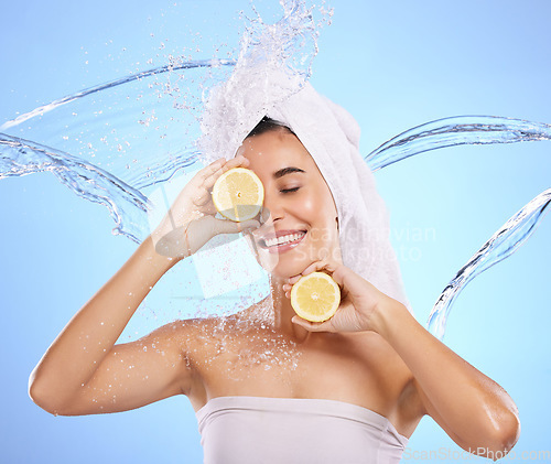 Image of Shower, lemon and water splash with woman in studio for natural cosmetics, beauty and mockup. Happy, fruits and spa hydration with female on blue background for vitamin c, face and skincare