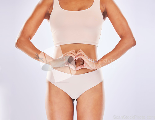 Image of Woman, heart and hands on stomach in studio as motivation for weight loss, diet or fitness. Female on a white background with hand emoji or shape for gut health, wellness or skin care in underwear